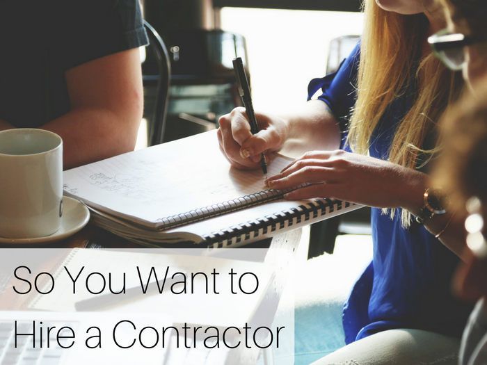 a team of people around a wooden table with a white woman writing on a notepad and the post title "So You Want to Hire a Contractor"